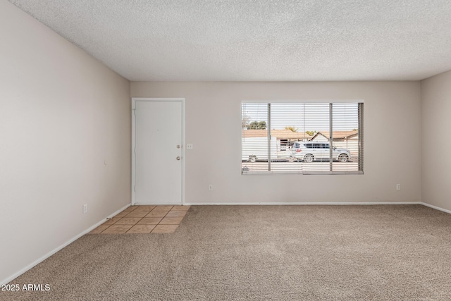 carpeted spare room with baseboards and a textured ceiling