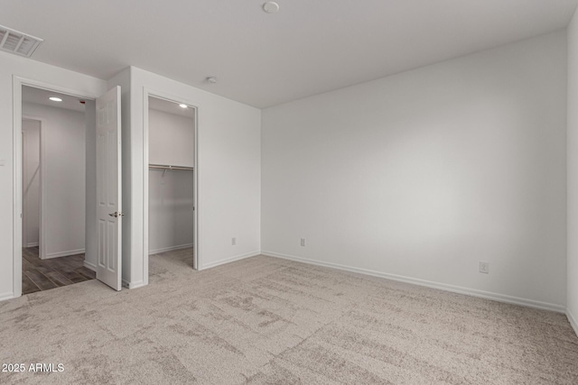 unfurnished bedroom featuring light colored carpet, a spacious closet, and a closet