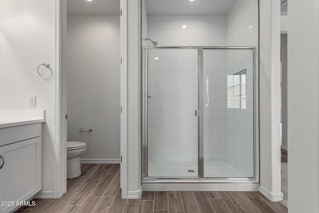 bathroom featuring vanity, toilet, and a shower with shower door