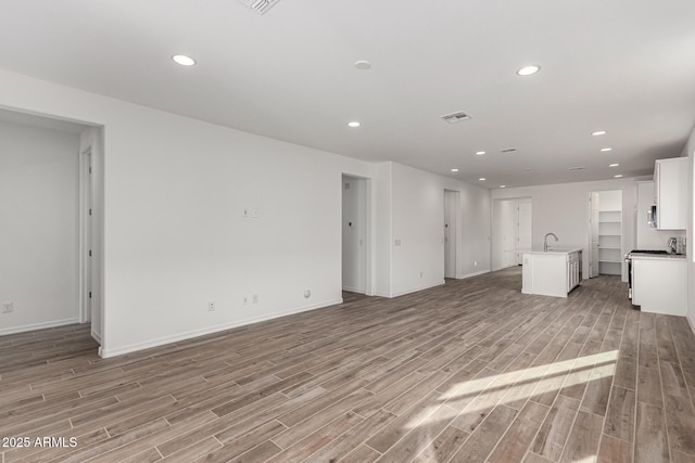 unfurnished living room featuring light wood-type flooring and sink