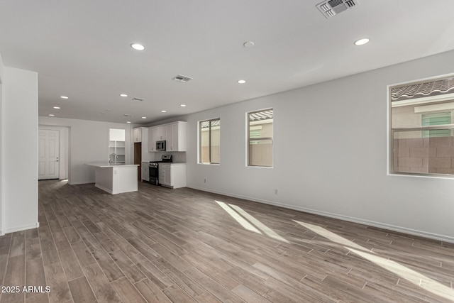 unfurnished living room featuring sink and light wood-type flooring