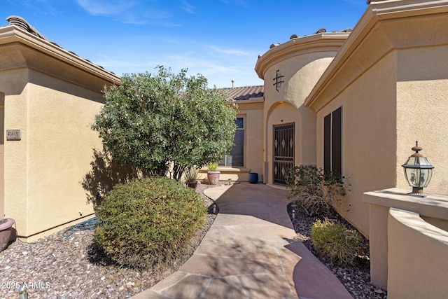 property entrance with a tiled roof, a patio area, and stucco siding