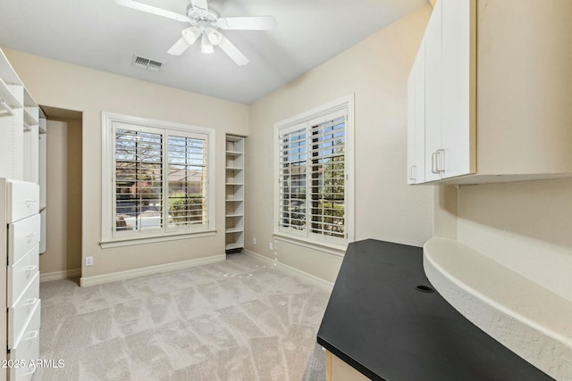 interior space featuring light carpet, ceiling fan, visible vents, and baseboards