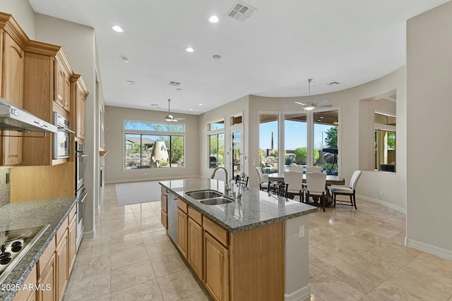 kitchen featuring a center island with sink, visible vents, dark stone counters, appliances with stainless steel finishes, and a sink