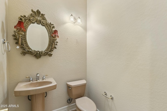 half bathroom with a textured wall and toilet