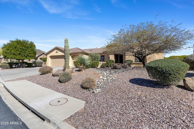 view of front of house with a garage, concrete driveway, a tiled roof, and stucco siding