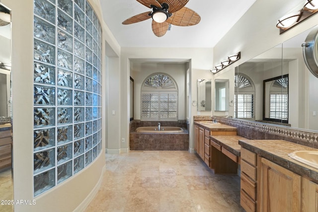 full bath featuring double vanity, a sink, a bath, and a ceiling fan