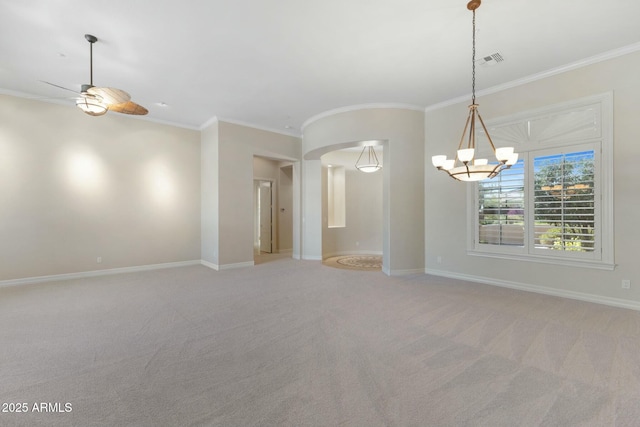 carpeted empty room with baseboards, visible vents, arched walkways, and ornamental molding