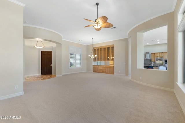 unfurnished living room with baseboards, light colored carpet, visible vents, and crown molding