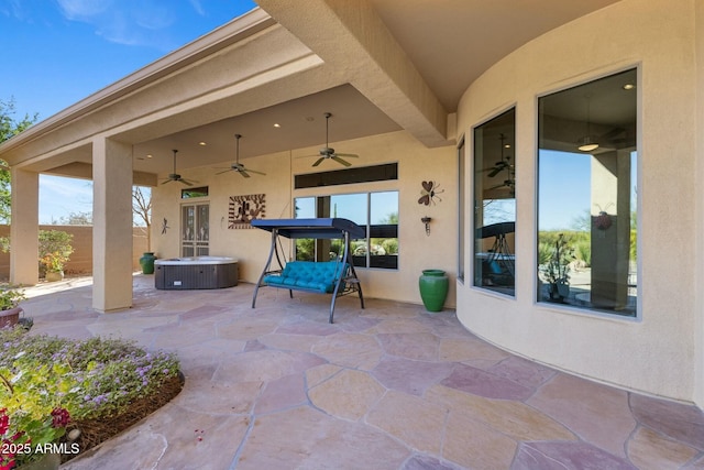 view of patio / terrace featuring a ceiling fan, fence, and a hot tub