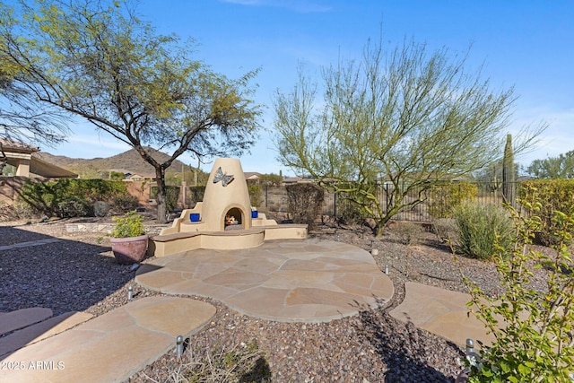 view of patio featuring a warm lit fireplace and fence