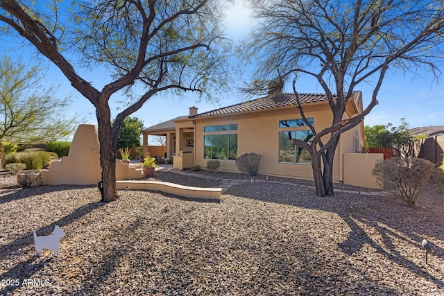 rear view of property featuring fence and stucco siding