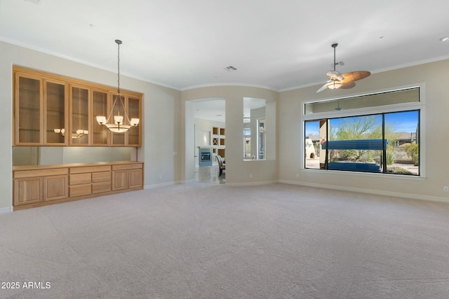 unfurnished living room with light carpet, baseboards, visible vents, arched walkways, and crown molding