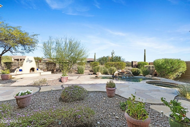 view of yard with a patio area, fence, an outdoor fireplace, and an in ground hot tub