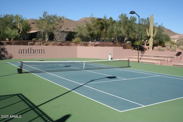 view of tennis court featuring a mountain view, community basketball court, and fence