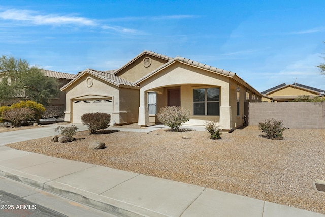 mediterranean / spanish house with concrete driveway, a tiled roof, an attached garage, fence, and stucco siding