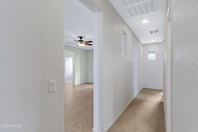 corridor featuring recessed lighting, visible vents, a textured wall, and baseboards