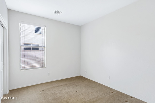 carpeted spare room featuring visible vents and baseboards