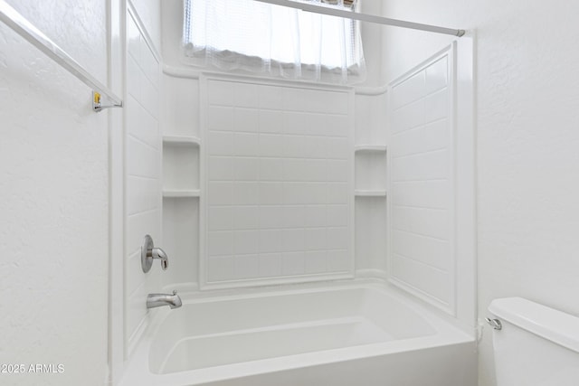 bathroom with a textured wall, shower / bathing tub combination, and toilet