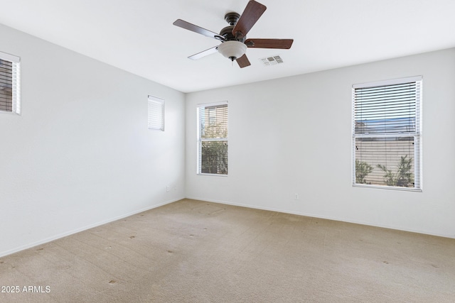 unfurnished room featuring light carpet, baseboards, visible vents, and a ceiling fan