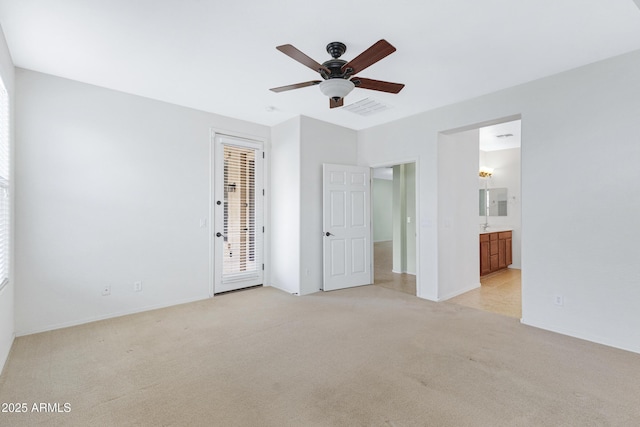 unfurnished bedroom featuring ceiling fan, light colored carpet, visible vents, access to outside, and ensuite bath