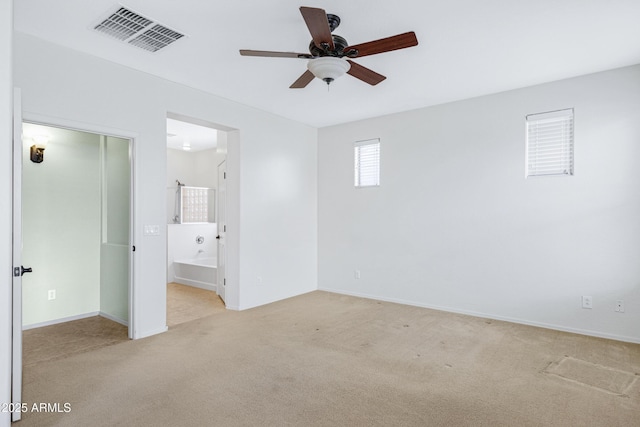 unfurnished bedroom with light colored carpet, visible vents, ceiling fan, ensuite bath, and baseboards