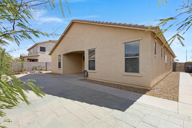 back of property featuring a patio, a fenced backyard, a tile roof, a gate, and stucco siding