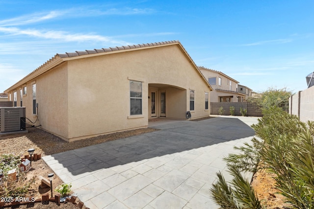 back of property with a patio, central AC unit, a fenced backyard, a tile roof, and stucco siding