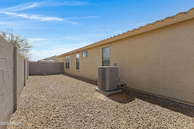 view of home's exterior with stucco siding, a fenced backyard, and central air condition unit