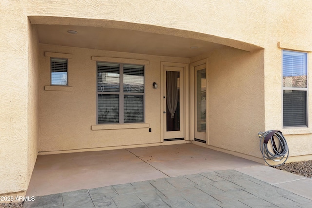 doorway to property with a patio area and stucco siding