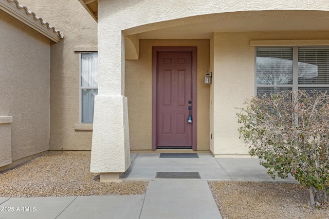 view of exterior entry with a tile roof and stucco siding