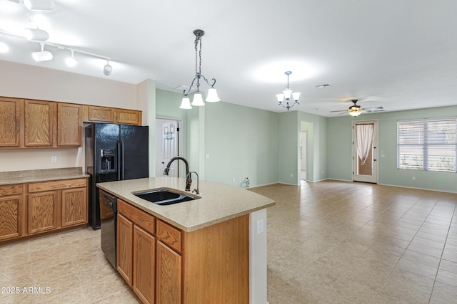 kitchen with a sink, black dishwasher, light countertops, hanging light fixtures, and brown cabinetry