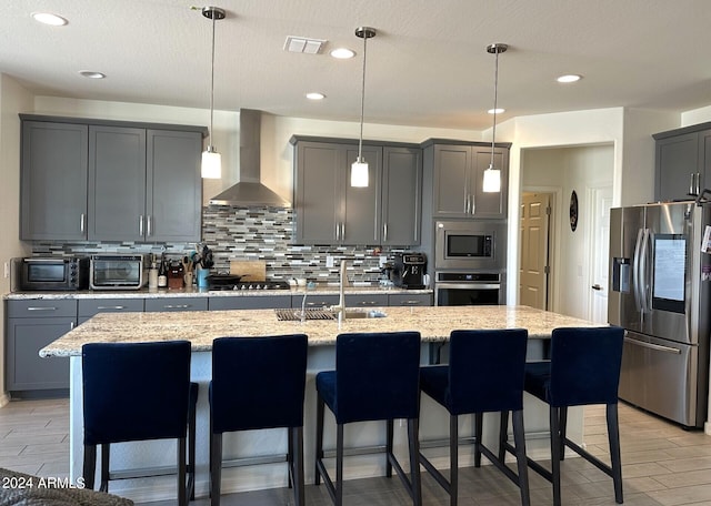 kitchen featuring appliances with stainless steel finishes, hanging light fixtures, and wall chimney exhaust hood