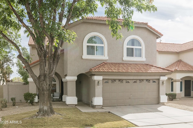 mediterranean / spanish-style house featuring concrete driveway, a tile roof, and stucco siding