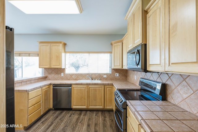 kitchen with dark wood-style flooring, tile countertops, light brown cabinetry, appliances with stainless steel finishes, and a sink