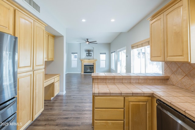 kitchen featuring visible vents, a ceiling fan, a glass covered fireplace, open floor plan, and light brown cabinetry