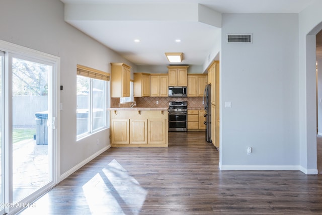 kitchen featuring arched walkways, appliances with stainless steel finishes, light brown cabinets, and visible vents