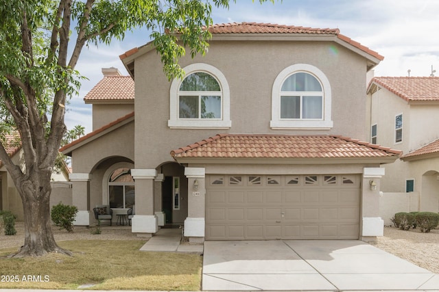 mediterranean / spanish home with driveway, an attached garage, a tile roof, and stucco siding