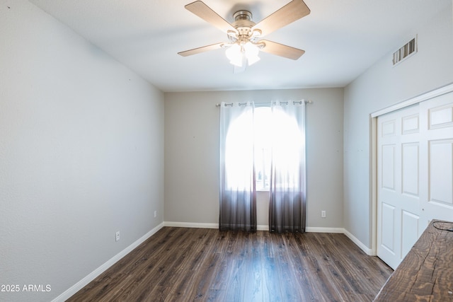 unfurnished bedroom featuring dark wood-style flooring, a ceiling fan, visible vents, baseboards, and a closet