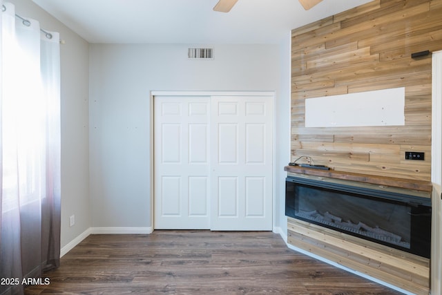 unfurnished bedroom featuring baseboards, visible vents, a ceiling fan, dark wood-style flooring, and a closet