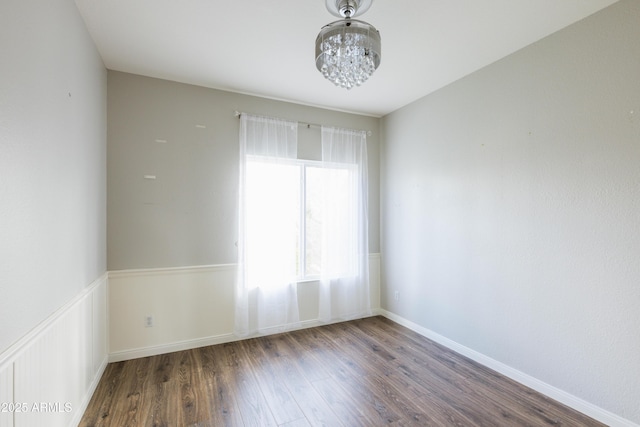 unfurnished room featuring a wainscoted wall and wood finished floors