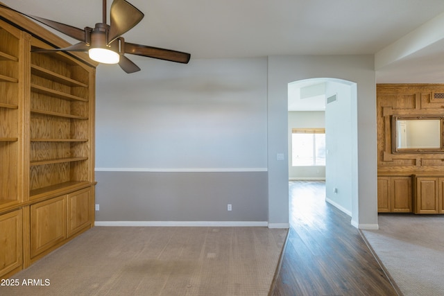 spare room featuring arched walkways, ceiling fan, wood finished floors, visible vents, and baseboards