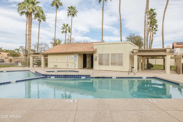 view of swimming pool with a patio area, a pool with connected hot tub, fence, and a pergola