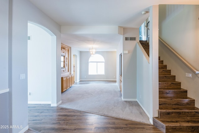 entryway with stairs, visible vents, baseboards, and wood finished floors