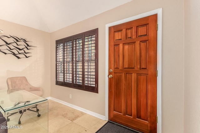 foyer entrance featuring vaulted ceiling, light tile patterned flooring, plenty of natural light, and baseboards