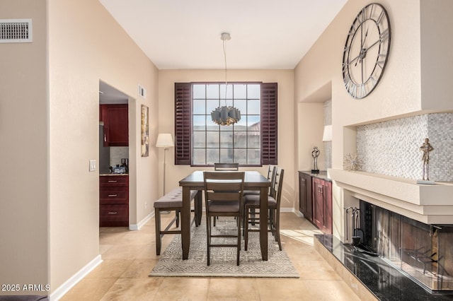 dining room featuring a multi sided fireplace, visible vents, and baseboards