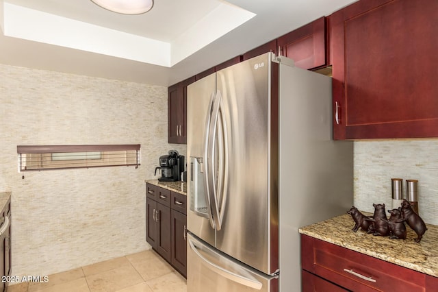 kitchen featuring light tile patterned floors, decorative backsplash, stainless steel fridge with ice dispenser, light stone counters, and dark brown cabinets