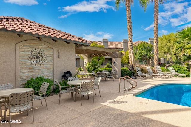 community pool with outdoor dining space, a patio area, and a pergola