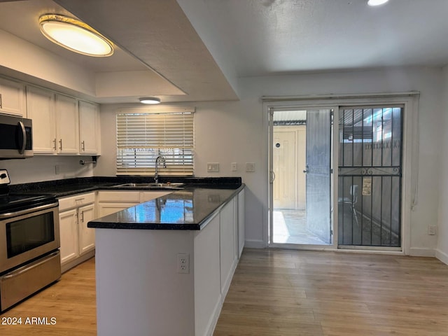 kitchen with sink, light wood-type flooring, white cabinetry, kitchen peninsula, and stainless steel appliances