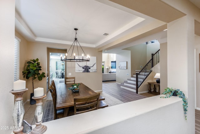 dining space with a tray ceiling, hardwood / wood-style floors, and a notable chandelier